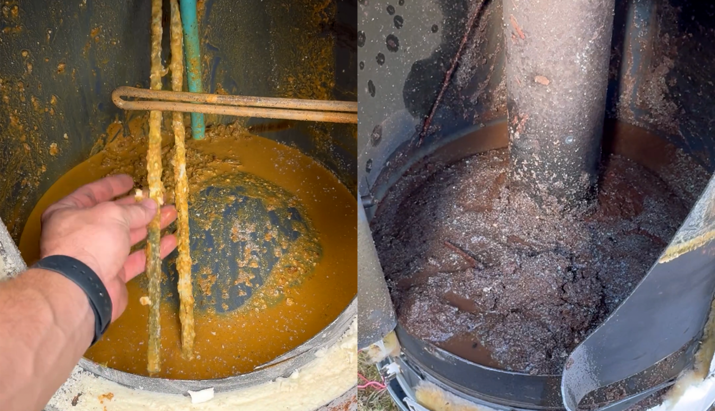 Rust and corrosion buildup inside a water heater tank, showing brown water and decayed metal surfaces.